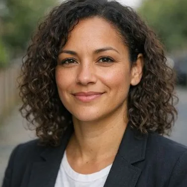 Woman mid-30s, loose curls, medium-light brown skin, dark blazer, relaxed expression